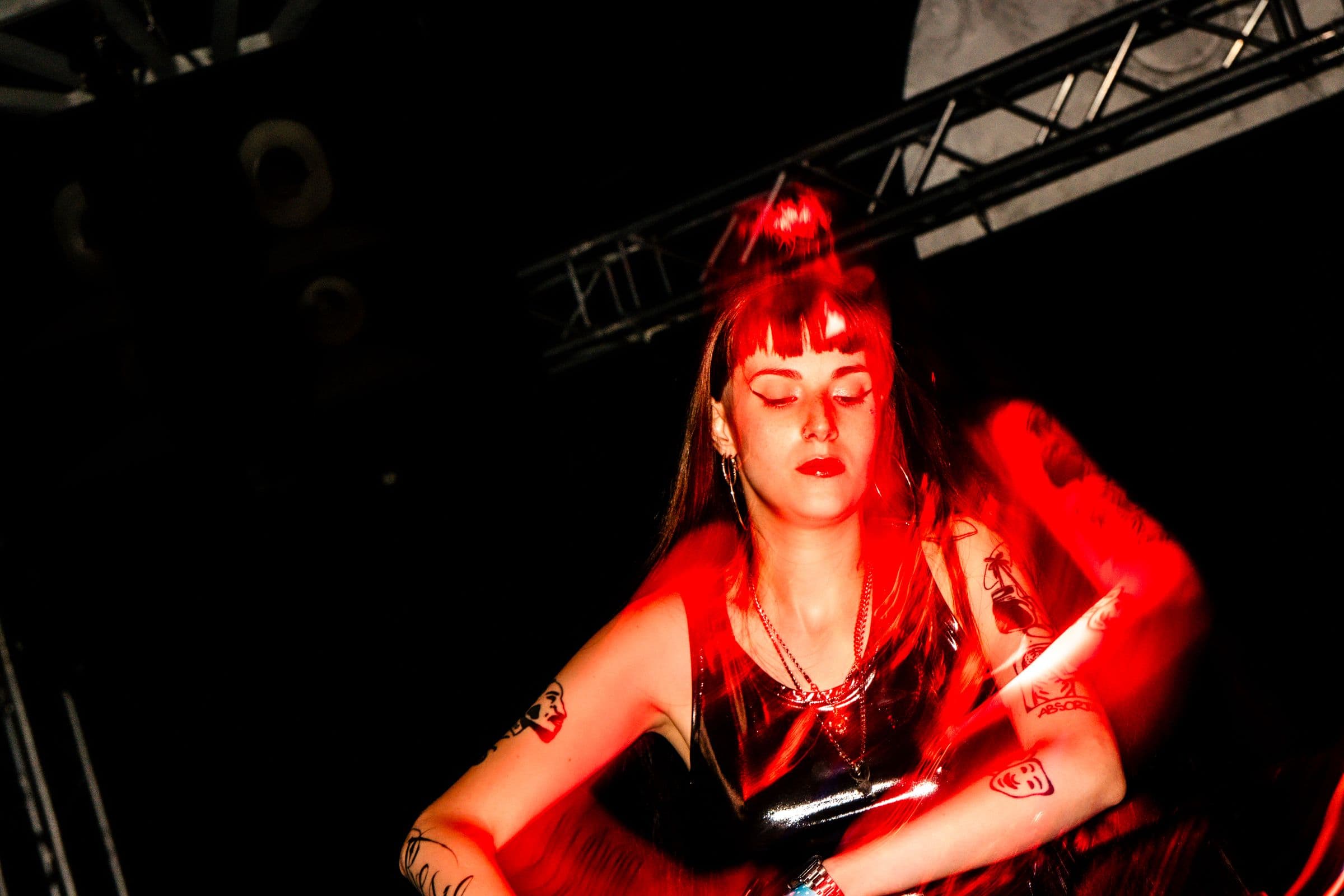 DJ do HER atrás da mesa, banhada em luz vermelha